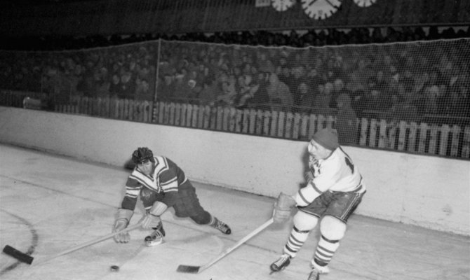 1956 год. Сборная СССР выигрывает второй титул чемпиона мира. На фото - Иван Трегубов (слева) в матче против сборной Канады.